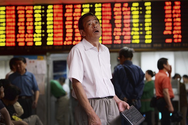 A man reacts as he looks at stock market prices at a brokerage house in Shanghai, China, Monday, June 29, 2015. Global stock markets sank Monday after Greece closed its banks and imposed capital controls in a dramatic turn in its struggle with heavy debts. the Shanghai Composite Index fell 3.3 percent to 4,053.03 despite China's surprise weekend interest rate cut. (Chinatopix via AP) CHINA OUT