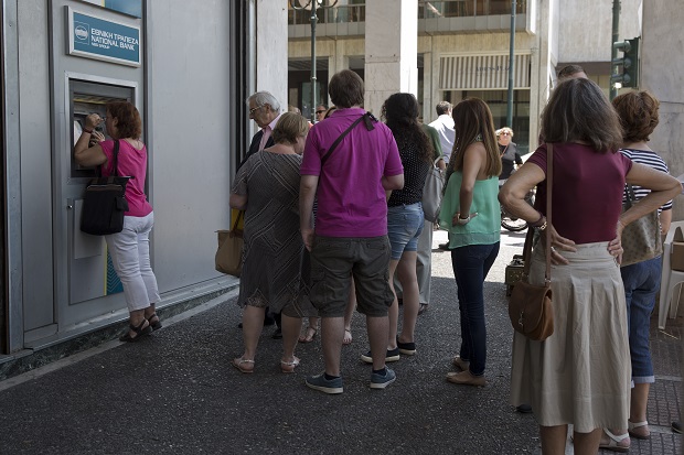 People line up at an ATM outside a National bank branch, in central Athens, on Monday, June 29, 2015. Anxious Greeks lined up at ATMs as they gradually began dispensing cash again on the first day of capital controls imposed in a dramatic twist in Greeces five-year financial saga. Banks will remain shut until next Monday, and a daily limit of 60 euros ($67) has been placed on cash withdrawals from ATMs. (AP Photo/Petros Giannakouris)