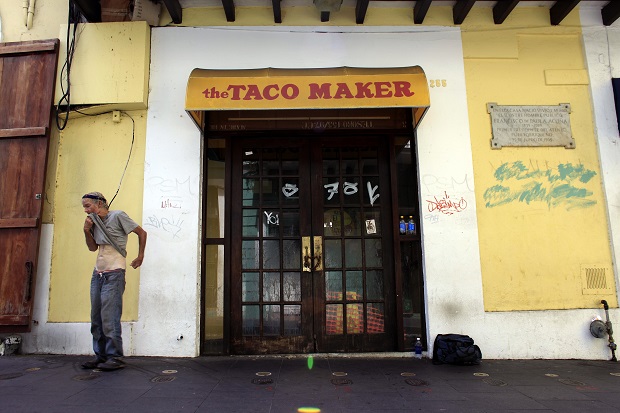 A homeless man stands in front of a closed down fast food restaurant in the colonial district of Old San Juan, Puerto Rico, Sunday, Aug. 2, 2015. As Puerto Rico's economy continues to decline a list of cost-cutting measures proposed by a group of hedge funds that holds $5.2 billion of Puerto Ricos debt has riled islanders: laying off teachers; cutting Medicaid benefits; and reducing subsidies to the main public university. (AP Photo/Ricardo Arduengo)