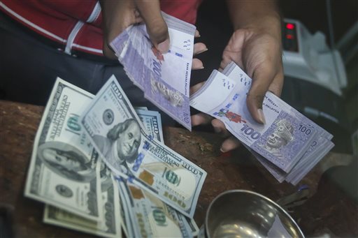 A currency trader calculates Malaysian ringgit notes at a currency exchange store in Kuala Lumpur, Malaysia on Tuesday, Sept. 29, 2015. The Malaysian ringgit closed at 4.457 against the US dollar on Tuesday. (AP Photo/Joshua Paul)
