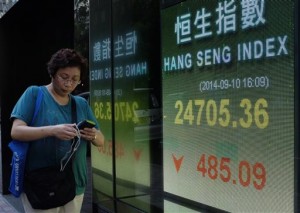 A woman walks past an electronic board of a local bank showing the Hong Kong share index in Hong Kong on Sept. 10, 2014. Asian markets were mixed Wednesday as bargain-buying was offset by the effects of a sell-off in New York and Europe in response to fresh data indicating weakness in the eurozone.  AP PHOTO/VINCENT YU