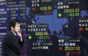 A man looks at an electronic stock board of a securities firm in Tokyo on Oct. 28, 2014. Asian stocks were mixed Thursday, Oct. 30, while the dollar resumed its upward march against the yen after the Federal Reserve wound up its vast bond-buying scheme and reiterated its plan to keep interest rates at record lows.  AP PHOTO/EUGENE HOSHIKO