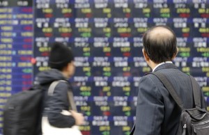 A man looks at an electronic stock board of a securities firm in Tokyo on Nov. 5, 2014. Asian stock markets mostly fell Wednesday as oil's fall to a three-year low weighed on energy companies and weaker European growth forecasts dampened sentiment.  AP PHOTO/SHIZUO KAMBAYASHI