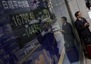 A man is reflected on an electronic stock board of a securities firm in Tokyo, Thursday, Nov. 6, 2014. Asian stock markets were mixed Thursday following a record close on Wall Street, while profit-taking sent Japan's Nikkei to its first loss since last week and the dollar retreated after breaking 115 yen.  AP PHOTO/EUGENE HOSHIKO