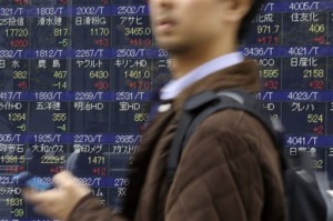A man walks past an electronic stock board of a securities firm in Tokyo Wednesday, Nov. 12, 2014. Asian stocks rose Wednesday, led by Tokyo's Nikkei index, which hit a fresh seven-year high as the yen slumped further amid speculation of a snap Japanese election.  AP PHOTO/EUGENE HOSHIKO 