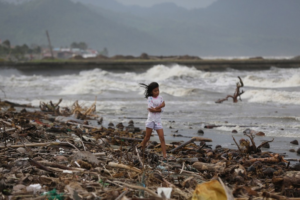 A girl walks along the shore as strong waves from Typhoon Hagupit hit Atimonan, Quezon province, eastern Philippines on Saturday, Dec. 6, 2014. Haunted by Typhoon Haiyan's massive devastation last year, more than 600,000 people fled Philippine villages and the military went on full alert Saturday to brace for a powerful storm only hours away from the country's eastern coast. (AP Photo/Aaron Favila