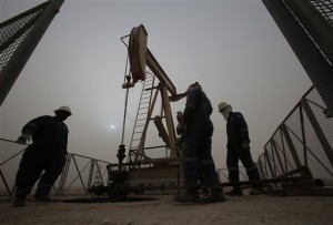In this Jan. 8, 2015, file photo, men work on an oil pump during a sandstorm in the desert oil fields of Sakhir, Bahrain. The price of oil dipped below $45 a barrel Tuesday, Jan. 13, 2015, following the latest sign from OPEC that the group doesn’t plan to cut production.  AP PHOTO/HASAN JAMALI 