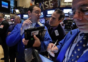 Traders Richard Scardino, left, and Gregory Rowe, center, confer on the floor of the New York Stock Exchange Monday, Jan. 5, 2015. US stocks closed lower Monday, led by declines in energy stocks as the price of oil plunged again.  AP PHOTO/RICHARD DREW