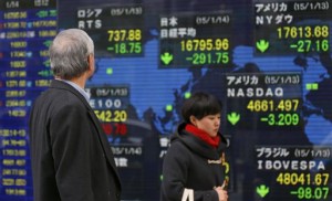 A man looks at an electronic stock indicator in Tokyo Wednesday, Jan. 14, 2015. Asian shares sank Wednesday following a volatile session on Wall Street as investors remained edgy over the slump in oil and metal prices.  AP PHOTO/SHIZUO KAMBAYASHI 