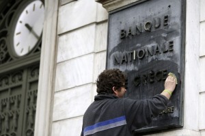 A worker cleans a marble sign that reads in French ''National Bank of Greece'' in Athens, on Monday, Feb. 9, 2015. Investors hammered Greece's markets Monday after the country's new government renewed a pledge to seek bailout debt forgiveness and dubbed the rescue package a "toxic fantasy"  comments that presage a clash with European lenders at high-stakes meetings this week. (AP Photo/Thanassis Stavrakis)
