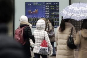 People walk past an electronic stock board of a securities firm in Tokyo Tuesday, Feb. 17, 2015. Asian stock markets were mostly higher Tuesday but gains were tempered after Greek debt talks broke down, raising the prospect Athens might leave the euro currency.  AP PHOTO/EUGENE HOSHIKO