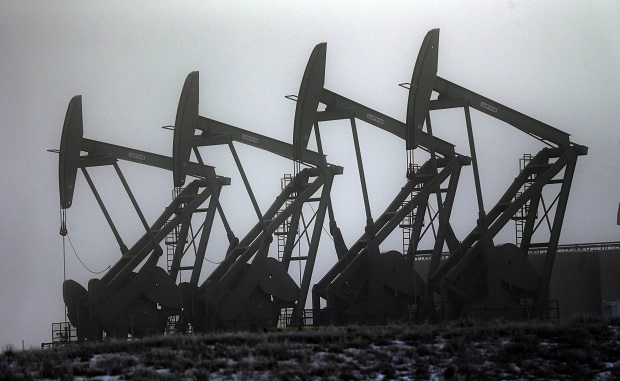 In this Dec. 19, 2014 photo, oil pump jacks work in unison, in Williston, N.D. After falling nearly 60 percent from a peak last June, the price of oil has now bounced back 19 percent since late January, closing Monday, Feb. 9, 2015 near $53. (AP Photo/Eric Gay)