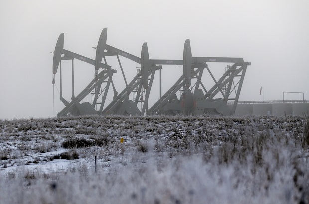 In this Dec. 19, 2014 photo, oil pump jacks work in unison on a foggy morning in Williston, N.D. High crude prices catapulted North Dakota into the top tier of the global oil market and helped double or triple the size of once-sleepy towns that suddenly had to accommodate a small army of petroleum workers. But now that those prices have tumbled, the shifting oil market threatens to put the industry and local governments on a collision course. (AP Photo/Eric Gay)