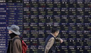 People walk past an electronic stock board of a securities firm in Tokyo on Tuesday, Feb. 3, 2015. Shanghai stocks tumbled Monday after two gauges of Chinese manufacturing activity showed contraction in January, while some Asian markets were also hit by a sell-off on Wall Street.  AP PHOTO/EUGENE HOSHIKO 