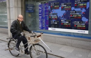 A man cycles past an electronic stock indicator in Tokyo on Wednesday, Feb. 4, 2015. Asia extended a global stocks rally Wednesday while the euro held on to healthy gains as hopes grow that Greece will be able to hammer out a debt deal with its European partners.  AP PHOTO/SHIZUO KAMBAYASHI 