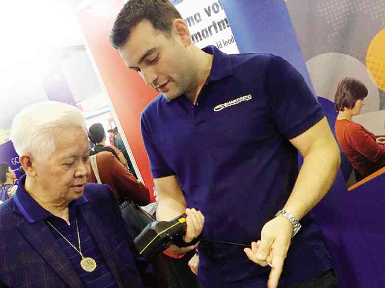 SMARTMATIC’S Cesar Flores (right) shows retired Comelec chair Sixto Brillantes the hardware that will help along the democratic process in the country.