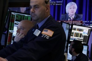 Traders work in a booth on the floor of the New York Stock Exchange, as Federal Reserve Chair Janet Yellen's news conference appears on a screen, Wednesday, March 18, 2015. Wall Street stocks surged Wednesday after the Federal Reserve trimmed its US economic forecast and signaled a cautious approach to raising interest rates.  AP PHOTO/RICHARD DREW 