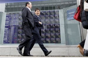 People walk past the stock prices displayed on an electronic board of a securities firm in Tokyo, Wednesday, March 4, 2015. Hong Kong and Shanghai markets sank in Asian trade Thursday after China set tepid 2015 economic and trade growth targets, while the euro fell to 11-year lows ahead of a key European Central Bank meeting.  AP PHOTO/SHUJI KAJIYAMA 