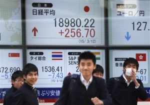 Students walk past an electronic board displaying Japan's Nikkei stock index and other financial indexes, in Tokyo on March 12, 2015. Major Asian markets mostly advanced Monday, March 23, following rallies on Wall Street and in Europe, while the dollar continued to struggle after the Federal Reserve dampened expectations for an early interest rate rise.  AP PHOTO/SHUJI KAJIYAMA 