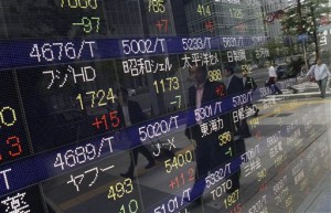 Pedestrians are reflected on an electronic stock board of a securities firm in Tokyo Tuesday, May 12, 2015. Asian stock markets were tepid Tuesday after the latest talks between Greece and its European creditors failed to reach agreement on bailout terms as the Greek government runs low on cash.  AP PHOTO/EUGENE HOSHIKO 