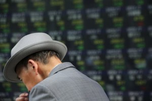A man walks past an electronic stock board of a securities firm in Tokyo on Thursday, May 14, 2015. Asian stock markets drifted Thursday after weak retail sales figures suggested the US economy is struggling to maintain growth momentum.  AP PHOTO/EUGENE HOSHIKO 