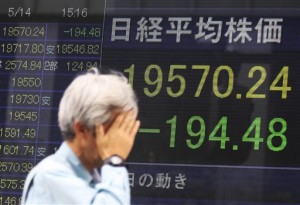 A man walks past an electronic stock board of a securities firm in Tokyo on May 14, 2015. Tokyo was the stand-out performer in Asian trade Monday, May 18, on upbeat corporate earnings and a record close on Wall Street, but Hong Kong retreated after its rally at the end of last week.  AP PHOTO/EUGENE HOSHIKO