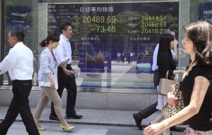 People walk by an electronic stock board of a securities firm in Tokyo on Monday, June 1, 2015. Asian markets mostly fell Tuesday, June 2, with Tokyo declining after a 12-day rally, while in Europe Greece's creditors held impromptu talks aimed at resolving the country's months-long debt crisis.  AP PHOTO/KOJI SASAHARA 