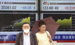 People wait for the traffic light to change to cross a street in front of an electronic stock board of a securities firm in Tokyo on June 15, 2015. Asian markets mostly rose Monday, June 22, after Greece gave creditors new proposals on reforming its bailout, fueling hopes of averting a default and possible exit from the eurozone.  AP PHOTO/KOJI SASAHARA 
