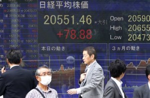 People walk past Japan's Nikkei stock index and other financial indexes displayed on an electronic board in Tokyo on May 28, 2015. Asian markets mostly fell Wednesday, while the euro edged higher following upbeat eurozone inflation data as traders track Greece's debt reform talks before a repayment deadline.  AP PHOTO/SHUJI KAJIYAMA