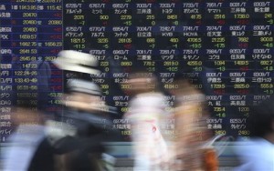 People walk past an electronic stock board of a securities firm in Tokyo on May 26, 2015. Asian markets fell Tuesday, June 9, with Shanghai and Hong Kong hit by another weak batch of indicators, but the euro was supported by upbeat German trade data.  AP PHOTO/EUGENE HOSHIKO 