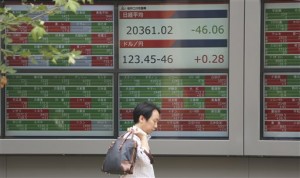 A man walks by an electronic stock board of a securities firm in Tokyo Monday, June 15, 2015. Asian stocks slipped and the euro sank Monday as Greece inched closer to a possible default after weekend talks with international creditors over freeing up the rest of its bailout funds went nowhere.   AP PHOTO/KOJI SASAHARA 