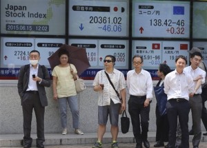 People wait for the traffic light to change to cross a street in front of an electronic stock board of a securities firm in Tokyo on Monday, June 15, 2015. The euro edged up in Asia Wednesday despite Greece hitting out at its creditors as its debt reform talks remain in stalemate, while stocks mostly rose after a positive lead from Wall Street ahead of a Federal Reserve policy meeting.  AP PHOTO/KOJI SASAHARA
