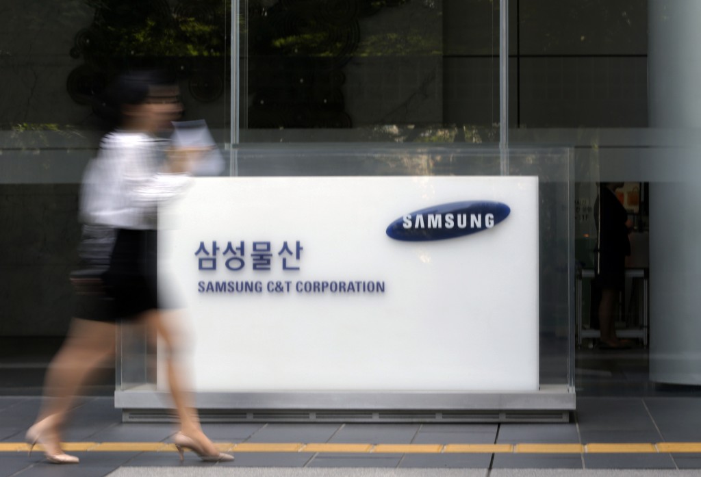 In this photo taken on May 26, 2015, an office worker walks by a logo of Samsung C&T Corp. at its head office in Seoul, South Korea. Thousands of South Korean investors are backing an American hedge funds bid to thwart a business combination between Samsung companies that they argue will only enrich the conglomerates wealthy founding family. (AP Photo/Lee Jin-man)
