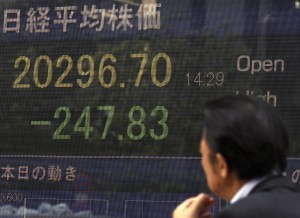 A man walks past an electronic stock board of a securities firm in Tokyo on Monday, July 27, 2015. The Shanghai share index dived more than 8 percent Monday as Chinese stocks suffered a renewed sell-off despite government efforts to support the market. Other Asian markets also were lower.  AP PHOTO/KEN ARAGAKI 