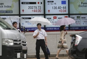 People stand in front of an electronic stock board of a securities firm in Tokyo, Wednesday, July 1, 2015. Asian shares rose on Wednesday as investors watched to see the next step as Greece fell into arrears after failing to make a debt repayment on Tuesday.  AP PHOTO/KOJI SASAHARA