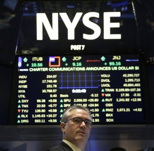 Trader Eric Schumacher stands under an electronic display on the floor of the New York Stock Exchange Thursday, July 9, 2015, in New York. US stocks gained Thursday, bouncing back from big losses a day earlier, as investors speculated that last-ditch talks between Greece and its creditors will produce an agreement.  AP PHOTO/SETH WENIG