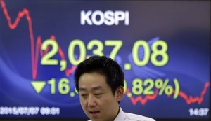 A currency trader walks by a screen showing the Korea Composite Stock Price Index (KOSPI) at the foreign exchange dealing room of the Korea Exchange Bank headquarters in Seoul, South Korea, Tuesday, July 7, 2015. Chinese stocks fell Tuesday despite official efforts to shore up slumping prices while other Asian markets were mixed after Greece's spiraling crisis weighed on Wall Street.  AP PHOTO/LEE JIN-MAN