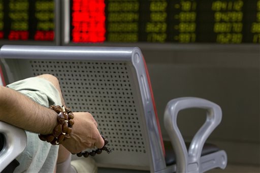 A Chinese investor holds prayer beads as he monitors stock prices at a brokerage house in Beijing, Tuesday, Aug. 25, 2015.  China's main stock market index has fallen for a fourth day, plunging 7.6 percent to an eight-month low. AP