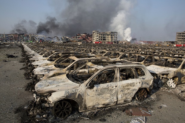 Smoke billows from the site of an explosion that reduced a parking lot filled with new cars to charred remains at a warehouse in northeastern China's Tianjin municipality, Thursday, Aug. 13, 2015. Huge, fiery blasts at a warehouse for hazardous chemicals killed many people and turned nearby buildings into skeletal shells in the Chinese port of Tianjin, raising questions Thursday about whether the materials had been properly stored. (AP Photo/Ng Han Guan)