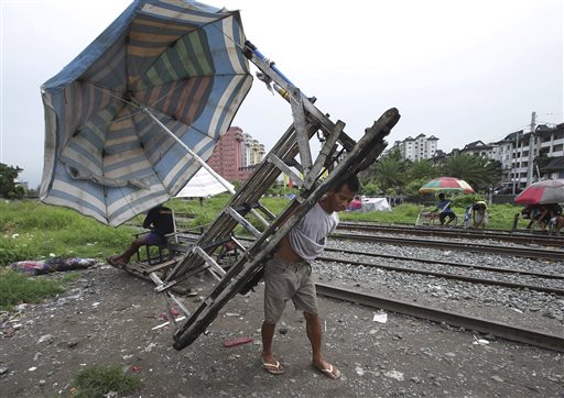 In this Wednesday, Aug. 12, 2015 photo, Filipino Ramil Santos parks his metal-wheeled cart with benches fashioned from scrap wood as he waits for passengers along the railway in Manila, Philippines. AP