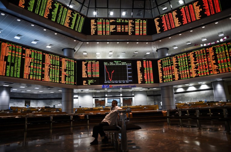 A man sits before electronic boards showing stock movements at the Malaysia Stock Exchange in Kuala Lumpur on July 28, 2015.  Asian markets tumbled further dragged down by another massive sell-off in Shanghai a day after the mainland Chinese market's heaviest one-day losses in more than eight years.  AFP PHOTO / MANAN VATSYAYANA
