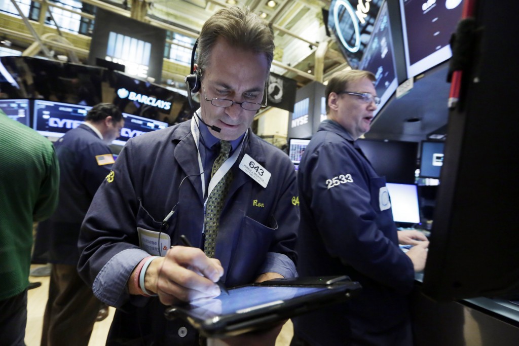Trader Ronald Madarsz, center, and specialist Patrick King, right, work on the floor of the New York Stock Exchange, Tuesday, Nov. 24, 2015. Stocks are opening modestly lower, following declines in Europe. (AP Photo/Richard Drew)
