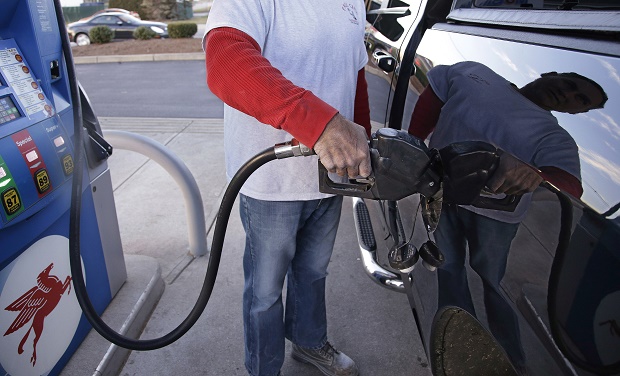 A customers prepares to pump gas on Monday, Dec. 7, 2015, at a gas station in Pembroke, Mass. The price of a barrel of oil fell Monday to a nearly seven-year low. With OPEC's decision to keep pumping at current levels, analysts expect oil to remain relatively cheap well into 2016 and maybe longer. (AP Photo/Stephan Savoia)