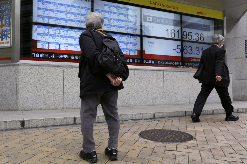 People walk past an electronic stock board showing Japan's Nikkei 225 at a securities firm in Tokyo, Friday, April 1, 2016. Asian stocks were lower on Friday with Tokyo stocks falling sharply after a closely-watched survey of Japanese businesses showed that confidence dropped more than expected last month. (AP Photo/Eugene Hoshiko)