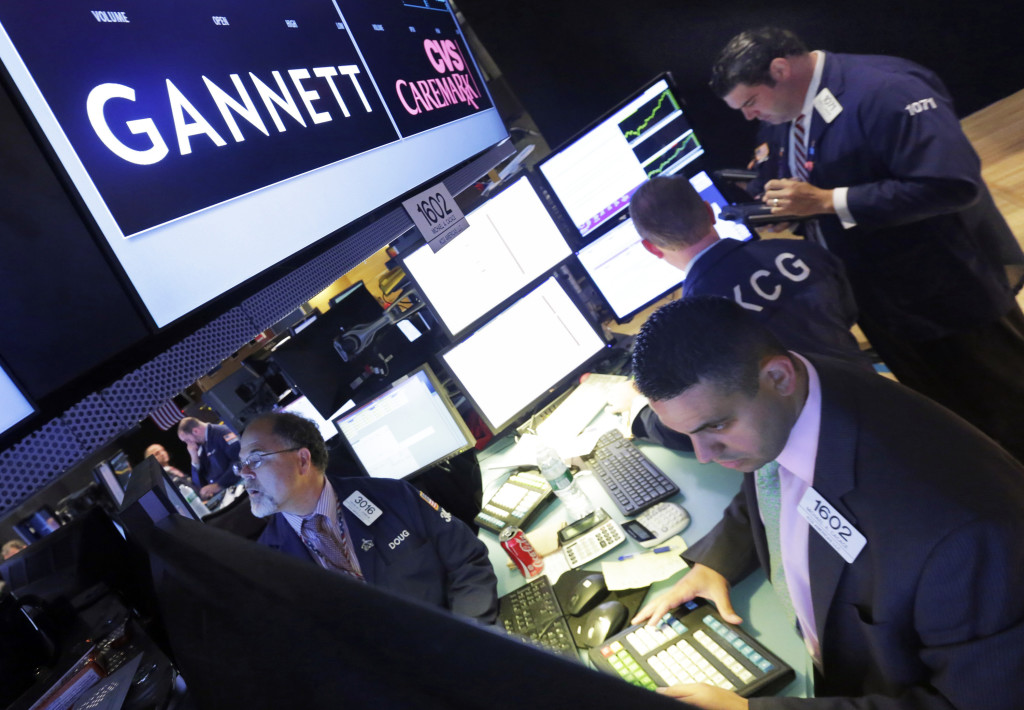 In this Tuesday, Aug. 5, 2014, file photo, specialist Michael Cacace, foreground right, works at the post that handles Gannett, on the floor of the New York Stock Exchange. Gannett reports financial results on Wednesday, April 27, 2016. (AP Photo/Richard Drew, File)