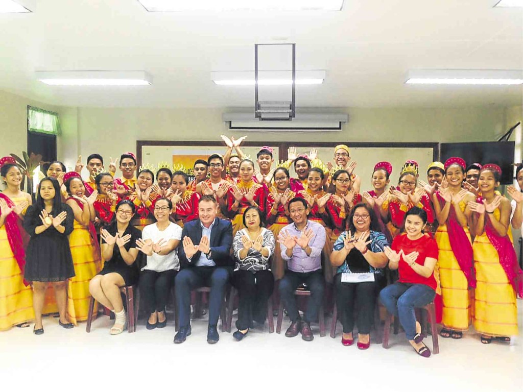 MEMBERS of the UP Rural High School glee club, Marife Maquera (second from left, seated) with Diageo PH head Jon Good (3rd from left, seated) put their hands together to form the “w” hand sign. Maquera, a music teacher, was among the 34 women selected by Diageo Philippines to train under Plan W, a community program to empower women through music. MARICAR CINCO/INQUIRER SOUTHERN LUZON