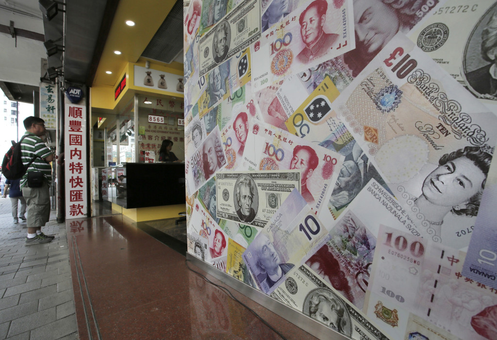 A man stands outside a money exchange shop decorated with different countries bank notes in Hong Kong, Monday, June 27, 2016. Japanese and Chinese stocks rose Monday but other Asian markets declined, crude prices fell further and U.S. shares appeared headed for a lower opening as jittery traders watched for more fallout from Britain's vote to exit the European Union. (AP Photo/Vincent Yu)