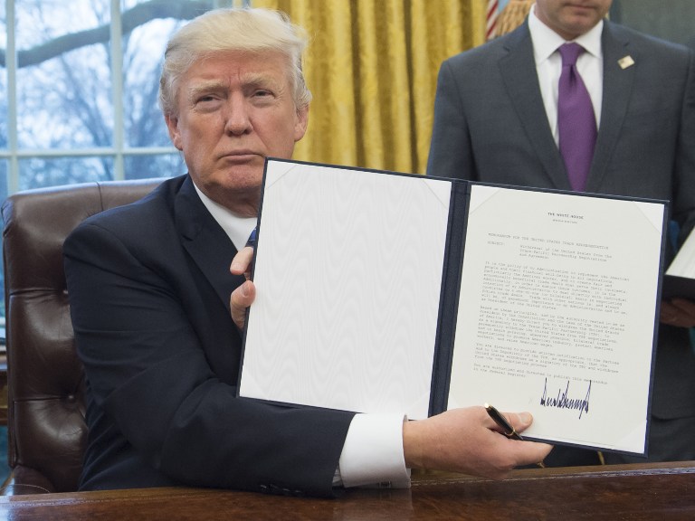 US President Donald Trump holds up an executive order withdrawing the US from the Trans-Pacific Partnership after signing it in the Oval Office of the White House in Washington, DC, January 23, 2017. Trump the decree Monday that effectively ends US participation in a sweeping trans-Pacific free trade agreement negotiated under former president Barack Obama. / AFP PHOTO / SAUL LOEB