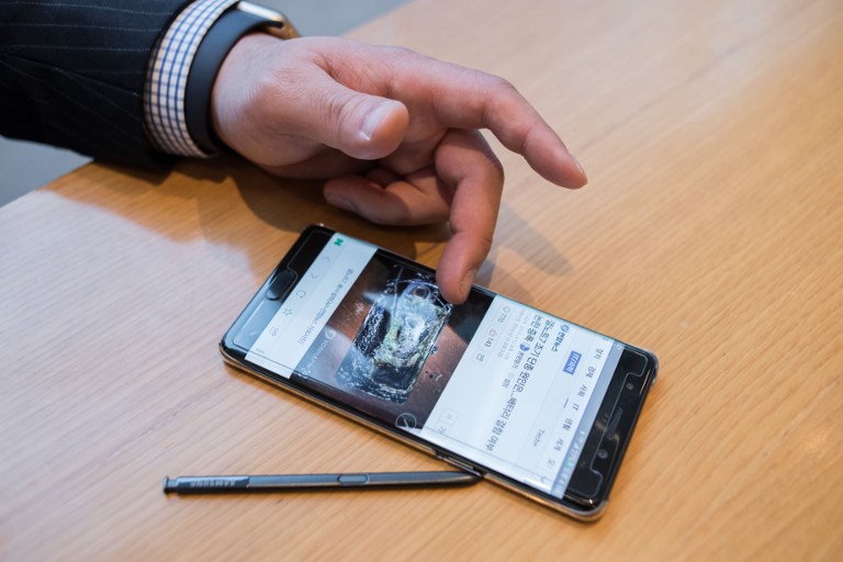 A Samsung customer browses a web page showing a fire-damaged Samsung Note 7 mobile phone, on a similar device, at a Samsung store in a mall beneath the company's headquarters in the Gangnam district of Seoul on October 12, 2016. Samsung Electronics slashed its third-quarter profit estimate by 33.3 percent, citing fallout from the recall nightmare surrounding its scrapped Galaxy Note 7 smartphone. / AFP PHOTO / Ed Jones