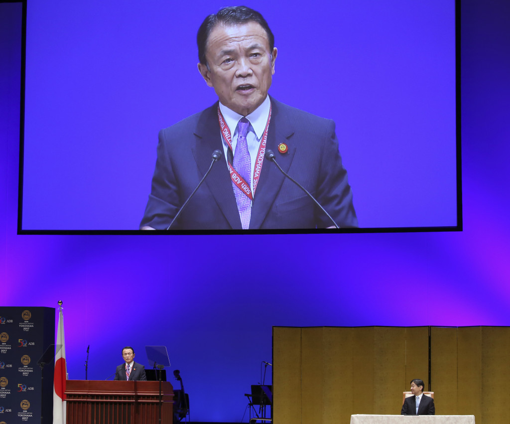 Japanese Finance Minister Taro Aso, left, delivers a speech as Japanese Crown Prince Naruhito listens during the opening session of the Asian Development Bank board of governors in Yokohama, Saturday, May 6, 2017. Investments should concentrate on high-quality projects to promote development that make technology available to all as the region stretches to make up for a shortfall in needed spending, the ADB's president and other leaders said Saturday. Aso said Japan, the biggest donor to the ADB, would contribute $40 million to a fund promote use of high technology. (AP Photo/Koji Sasahara)
